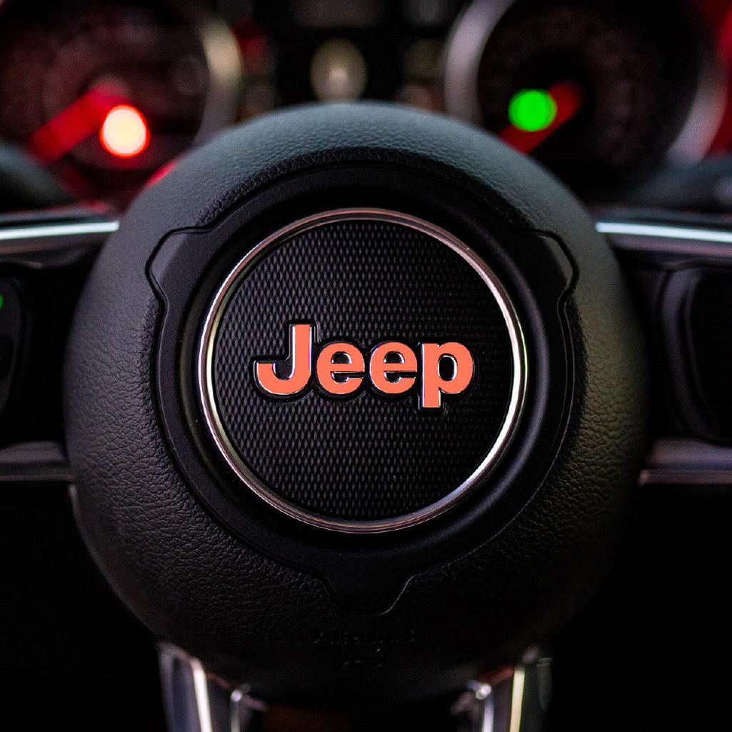 Close-up of a coral Jeep steering wheel with logo
