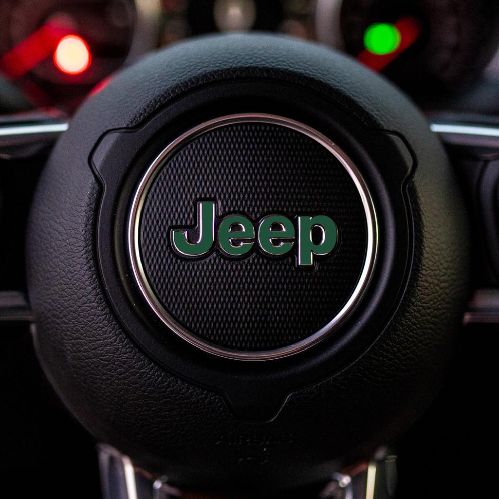 Steering wheel with dark green Jeep logo in a car interior
