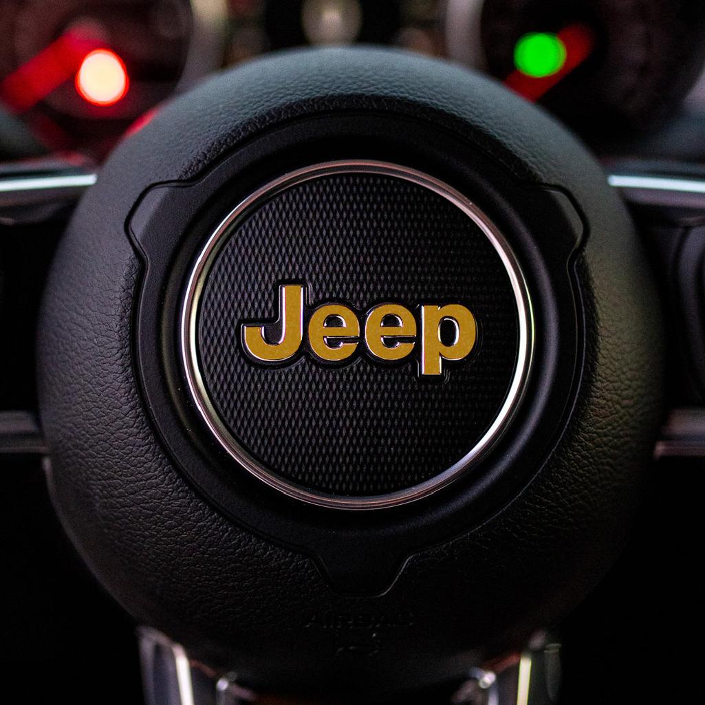 Steering wheel with gold Jeep logo in a car interior