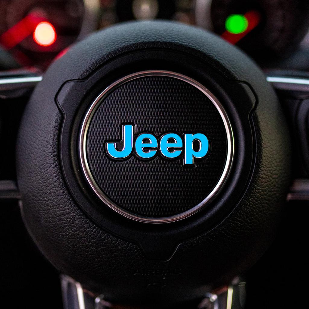 Steering wheel with light blue Jeep logo in a car interior