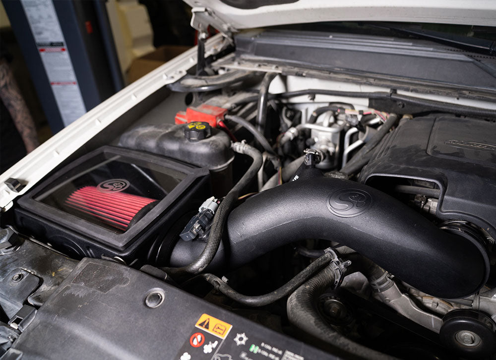 Cold Air Intake for 2009-2013 Silverado, Sierra 1500 / 2009-2014 Tahoe, Yukon, Suburban, Escalade on a white background installed in the engine compartment of a vehicle.

