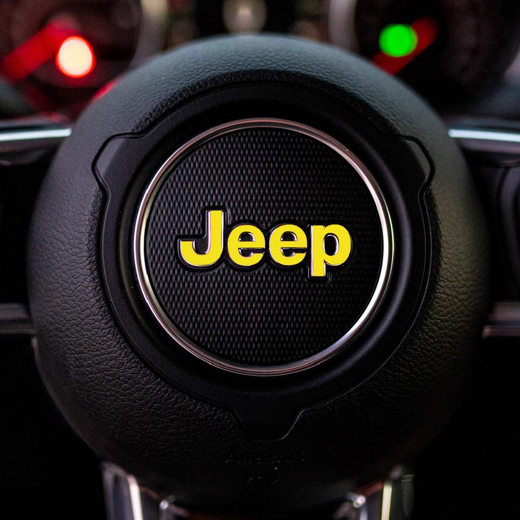 Steering wheel with yellow Jeep logo in a car interior