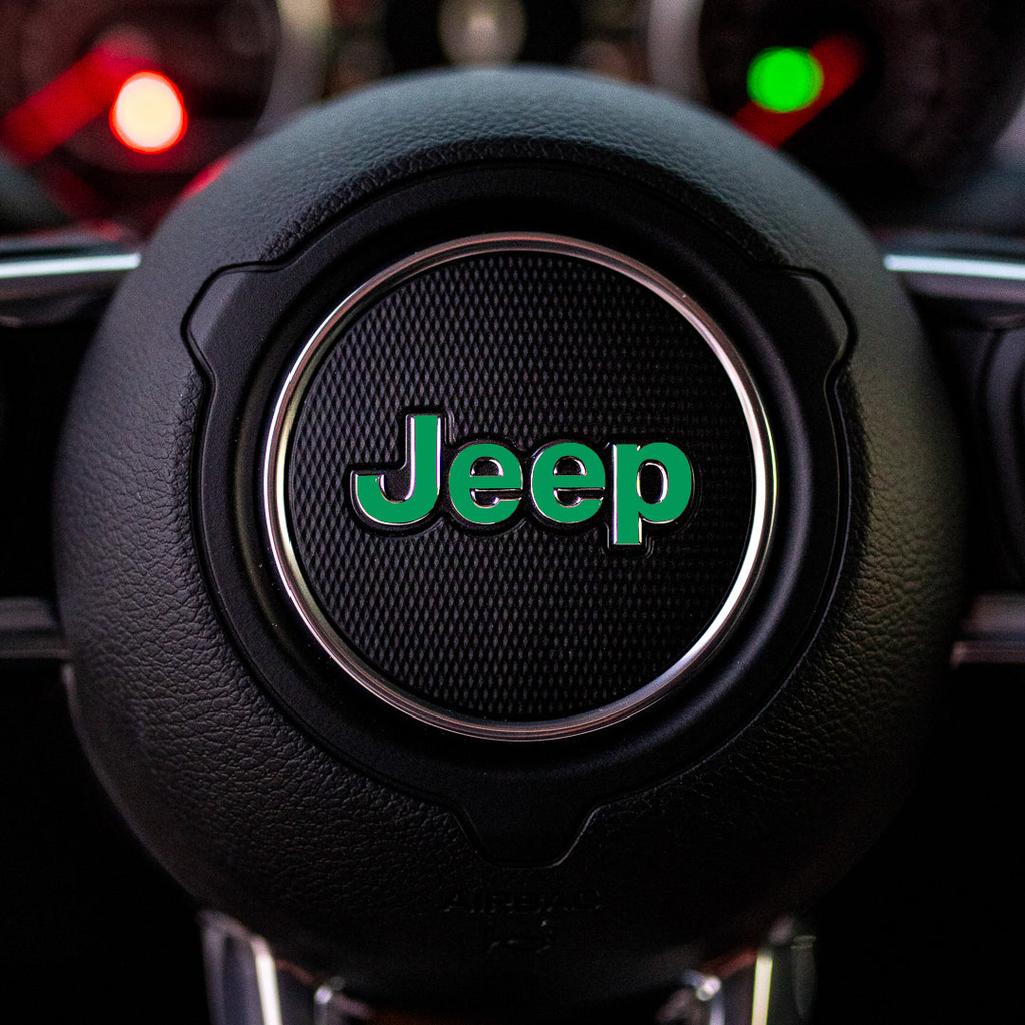 Steering wheel with green Jeep logo in a car interior