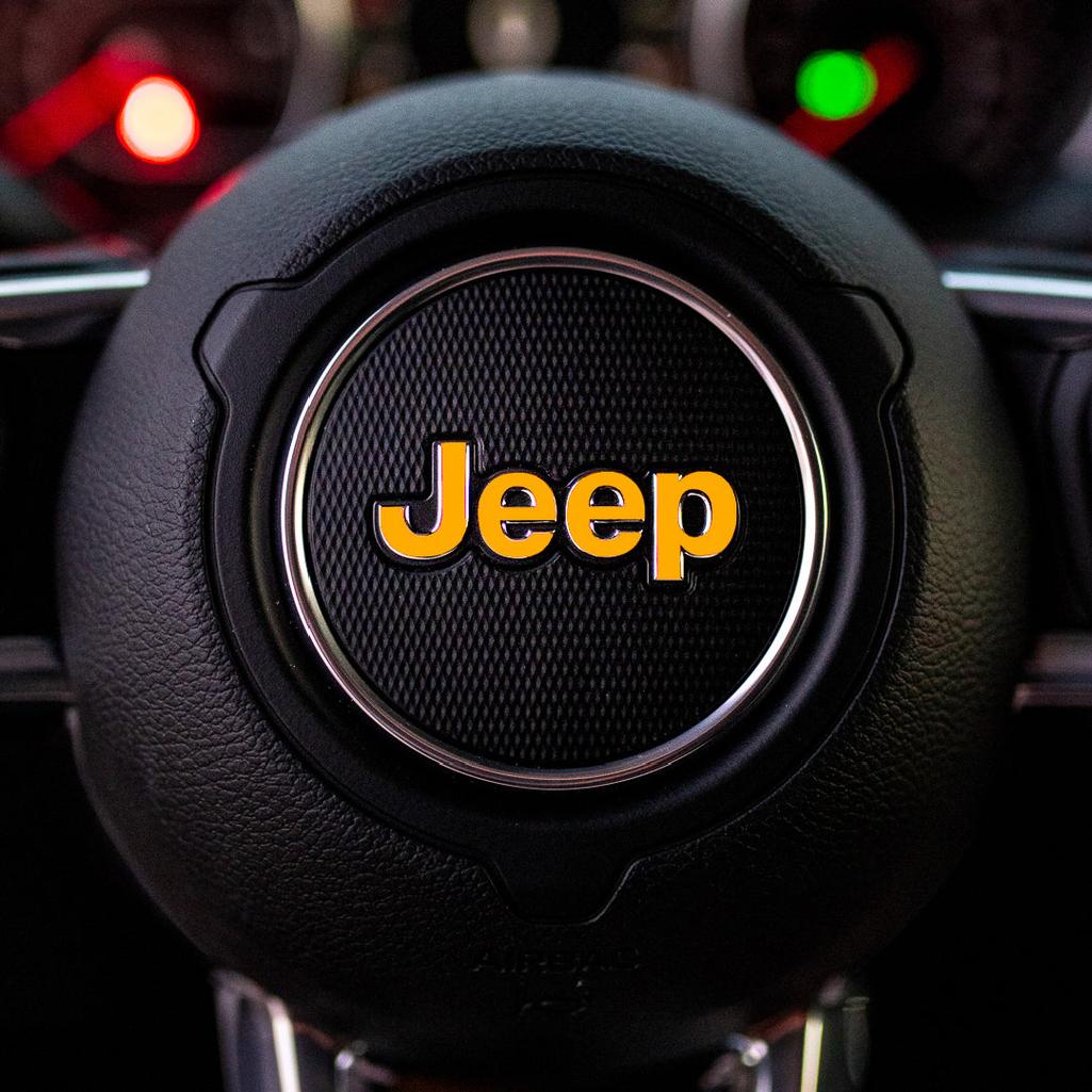 Steering wheel with golden yellow Jeep logo in a car interior
