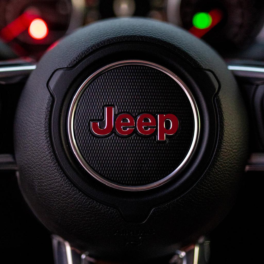 Close-up of a maroon Jeep steering wheel with the brand logo.
