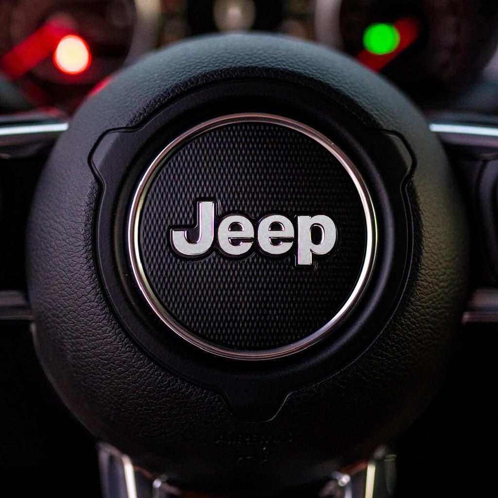 Steering wheel with silver Jeep logo in a car interior