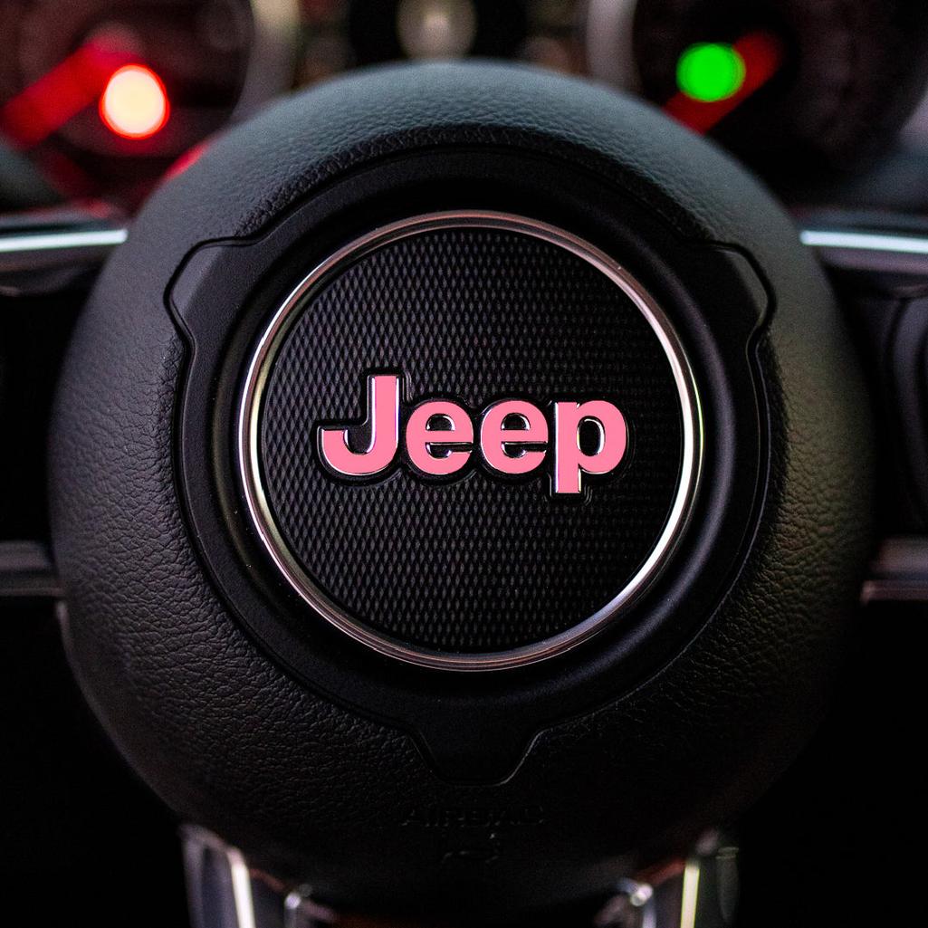 Steering wheel with soft pink Jeep logo in a car interior