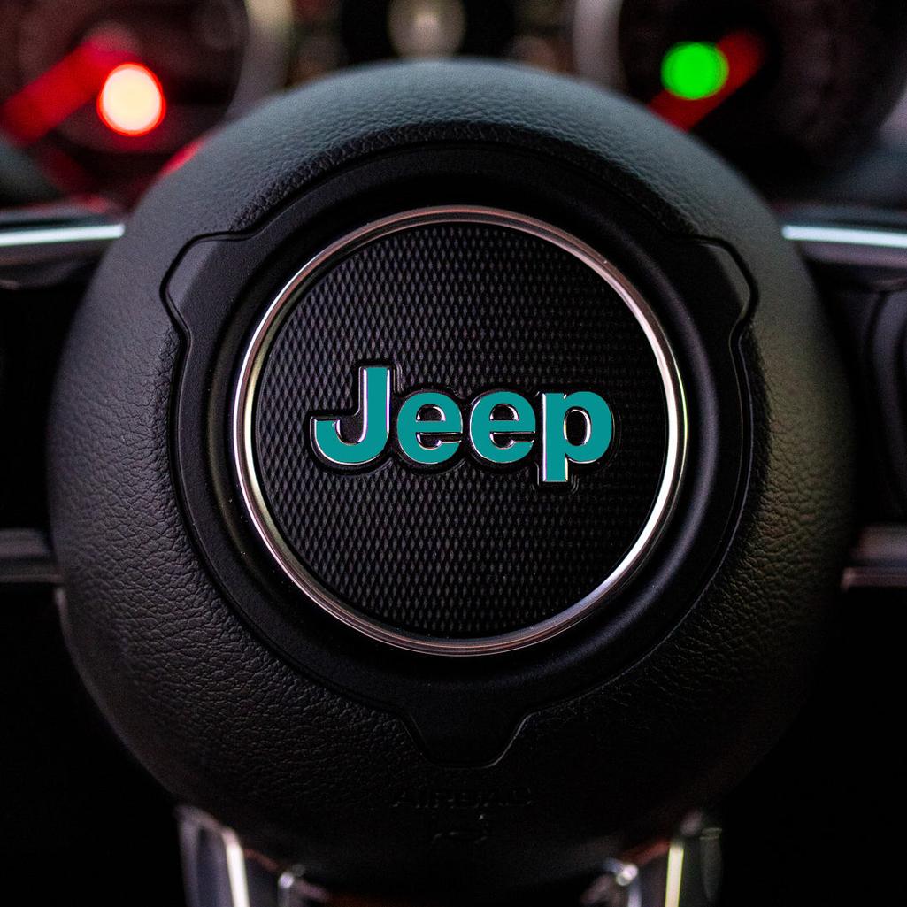 Steering wheel with turquoise Jeep logo in a car interior